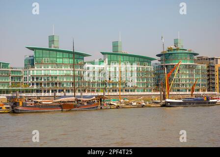 Una tenuta con moderni edifici residenziali verdi di forma originale sul Fiume Tamigi. Ci sono chiatte ormeggiate sul fiume. Architettura di Londra, Foto Stock