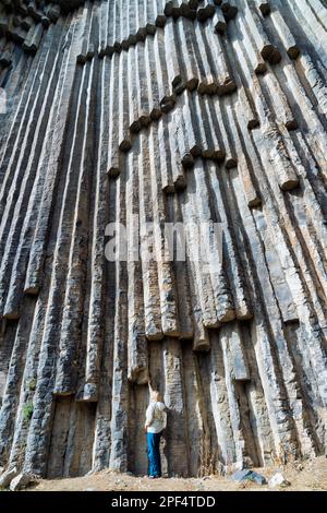 Sinfonia di pietre, donna sotto la formazione di colonna di basalto lungo la gola di Garni, Provincia di Kotayk, Armenia, Caucaso, Medio Oriente Foto Stock