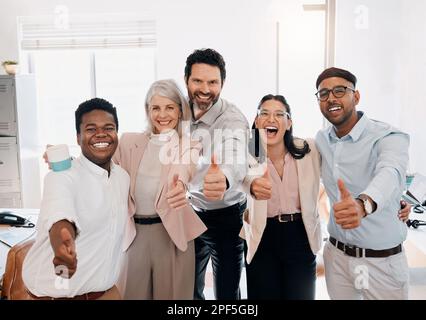Possiamo farlo. un gruppo diversificato di uomini d'affari in piedi in ufficio e mostrando un pollice in su. Foto Stock