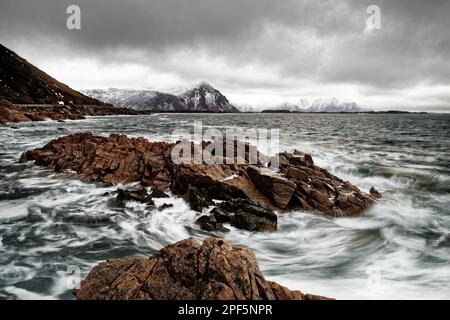 Paesaggio costiero in Norvegia in inverno con il movimento dell'acqua tra grandi pietre, il movimento dell'acqua è stato congelato da una breve esposizione lunga, nel backgroun Foto Stock