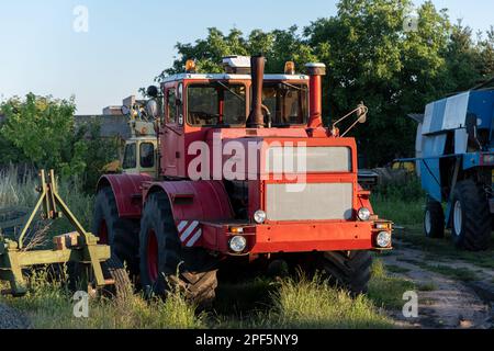 Vecchio retro vecchio colore rosso abbandonato trattore arrugginito si trova vicino alla fattoria per lavori sul campo. Foto Stock