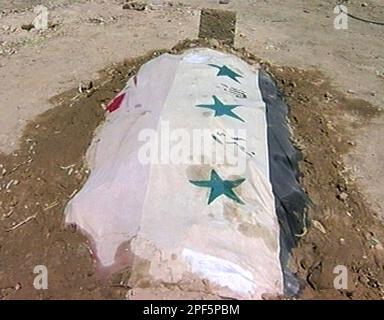 The unmarked grave of one of the elder sons of former Iraqi dictator Saddam Hussein is seen in the family cemetery in Tikrit, Iraq, on Saturday Aug. 2, 2003, wrapped in flags for a martyr's burial. The leaders of Saddam Hussein's tribe buried the ousted dictator's sons Odai and Qusai, together with Qusai's son Mustafa, who died together during a gun battle with US troops in Mosul on July 22. (AP photo / APTN)