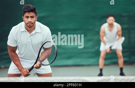 Due giocatori di tennis etnici che tengono racchette e pronti a giocare a gioco di campo. Atleti seri e concentrati insieme in posizione. Giocare a due giocatori competitivi Foto Stock