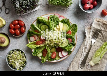 Insalata di verdure con germogli di ravanello, tomatos e avocado, con broccoli freschi e cavolo microgreno sullo sfondo Foto Stock