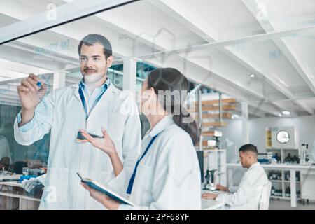 Utilizzare i dati per trarre conclusioni e interpretarli. due giovani scienziati che si occupano di brainstorming con note su uno schermo di vetro in un laboratorio. Foto Stock