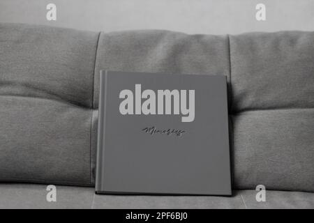 Un album fotografico grigio con copertina in pelle con ricordi stampati su un divano grigio Foto Stock