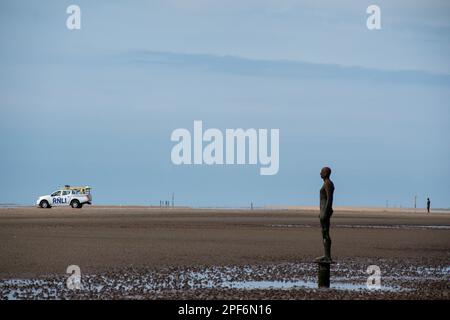 Figura dall'installazione dell'artista Antony Gormley un altro posto su Crosby Beach rivolto verso il mare con un RNLI LIFE Guard 4x4 sullo sfondo Foto Stock