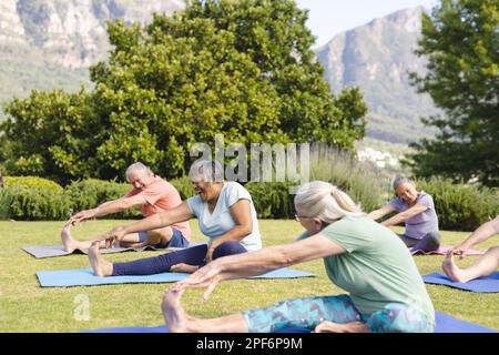 Felice gruppo di amici anziani che praticano yoga e stretching in giardino Foto Stock