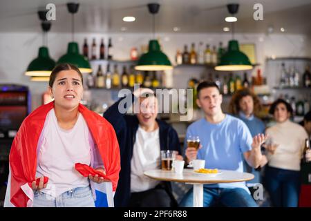 Compagnia di giovani tifosi adulti con bandiera nazionale d'Inghilterra sconvolta per la squadra preferita che perde partita in bar Foto Stock