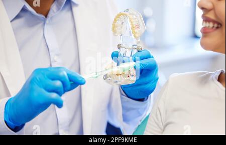 Lo faccia come il vostro dentista lo fa. un dentista che mostra al paziente un modello di denti prima della sua procedura. Foto Stock