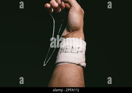 Non prendere decisioni permanenti sul dolore temporaneo. un uomo irriconoscibile con bende avvolte intorno al polso mostrando aiuto scritto su di esso. Foto Stock