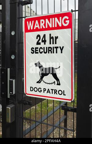 Segnale di pattuglia di sicurezza con cane di guardia. Warning Guard Dogs on Duty segnale di testo su un cancello. segnale di avvertimento per pattuglia di cani di sicurezza 24 ore su 24. Nessuno, foto di strada, Foto Stock