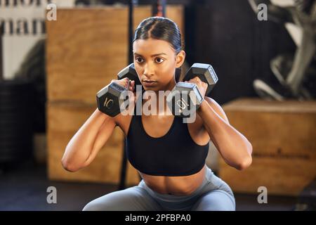 Mostra quei dumbbells whos boss. una giovane donna che si allenava con i pesi in palestra. Foto Stock