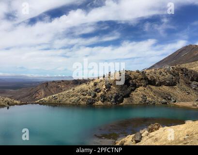 Qualche escursionista che riposa sulle rive di uno dei tre Laghi di Smeraldo in cima al Tongariro alpine crossing Foto Stock