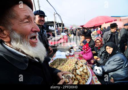 Un anziano uomo Uighur che mangia Samsa - un tradizionale tandoor forno pasta ripiena di carne. Foto Stock