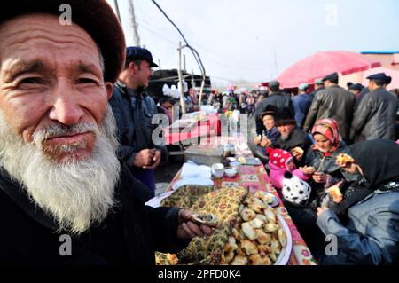 Un anziano uomo Uighur che mangia Samsa - un tradizionale tandoor forno pasta ripiena di carne. Foto Stock