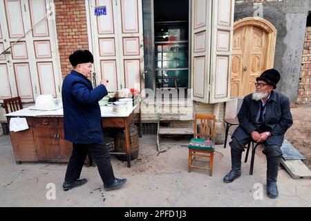 Uomini di Uyghur seduti in un negozio nella città vecchia di Kashgar, Xinjiang, Cina. Foto Stock