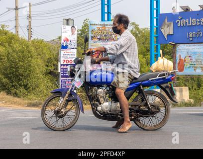 BANGKOK, THAILANDIA, MAR 11 2023, Un uomo a piedi nudi con una moto è in piedi a un bivio Foto Stock