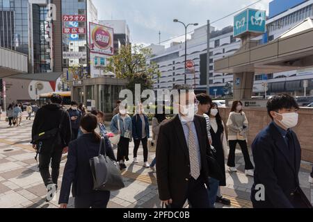 I pedoni camminano di fronte alla stazione della metropolitana di Ikebukuro a Tokyo. Il Giappone ha allentato le linee guida COVID-19 per indossare la maschera il 13 marzo 2023. Foto Stock