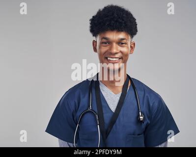 Im qui per fornirvi la cura che meritate. un'infermiera maschile che si posa con uno stetoscopio intorno al collo. Foto Stock