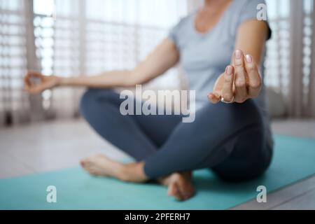Lasciatemi essere per un po'. una donna irriconoscibile meditando sul pavimento a casa. Foto Stock
