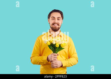 Ritratto di felice giovane isolato su sfondo turchese con bouquet di tulipani Foto Stock