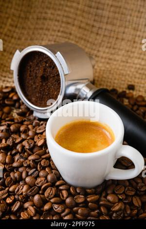 Caffè macinato o usato con portafiltro e una tazza di caffè appena preparato sullo sfondo Foto Stock