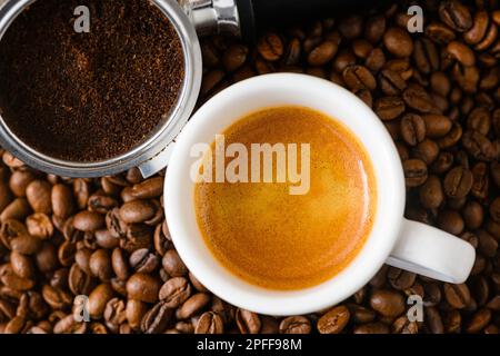 Caffè macinato o usato con portafiltro e una tazza di caffè appena preparato sullo sfondo Foto Stock