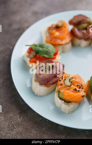 Antipasti esotici serviti al piatto. Tartine con pesce salmone e carne a fette preparate per mangiare Foto Stock