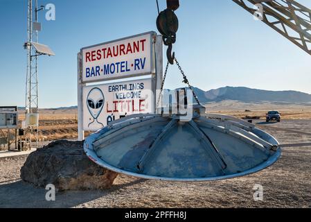 Si è schiantato UFO, appeso al braccio di un carro attrezzi, installazione locale d'arte, segno piccolo A’le’Inn motel, Extraterrestre Hwy NV-375, a Rachel, Grande Bacino Nevada Foto Stock