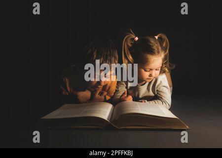 i bambini che si trovano al buio leggendo un libro Foto Stock