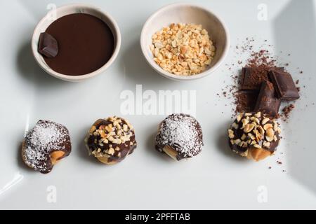 Deliziosi profiteroles con cioccolato, presentazione di profiteroles con nocciola e cioccolato in un piatto bianco, vista dall'alto. Foto Stock