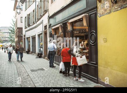Strasburgo, Francia - 28 ottobre 2022: In una vivace via dello shopping a Strasburgo, Francia, un gruppo di persone a piedi dalla vetrina di LRT Du Parfu Foto Stock
