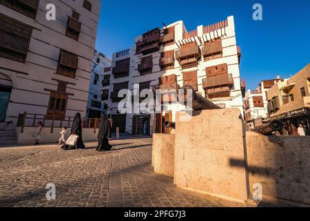 Vista delle donne arabe in abaya con i bambini che passano il cannone in via Souk al Alawi nel quartiere storico di al-Balad, Jeddah, KSA, Arabia Saudita Foto Stock