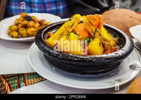 Tajine o tagine - piatto tradizionale berbero servito in una ciotola di terracotta nera presso un tipico ristorante di strada marocchino, dettaglio closeup Foto Stock