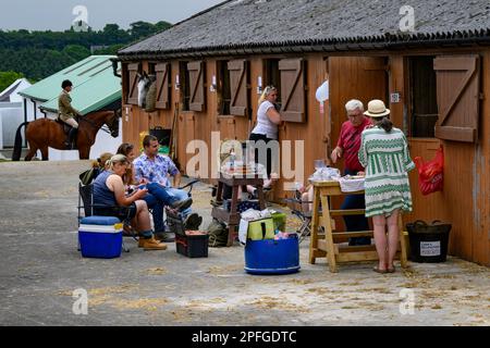 I proprietari di scuderie e cavalli chiacchierano rilassandosi in un cortile stabile, condividendo e mangiando pranzo all'aperto presso lo showground - Great Yorkshire Show, Harrogate, England, UK. Foto Stock