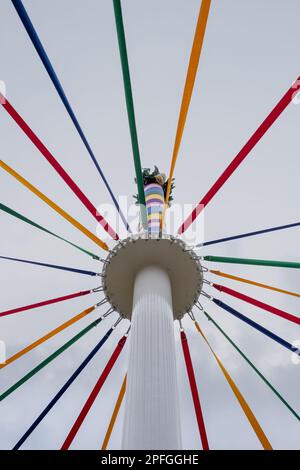 Un tiro a basso angolo di un classico inglese Maypole durante un festival di danza sotto un cielo nuvoloso Foto Stock