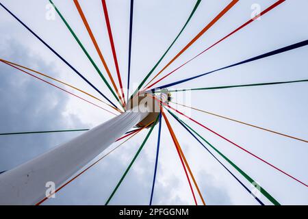 Un tiro a basso angolo di un classico inglese Maypole durante un festival di danza sotto un cielo nuvoloso Foto Stock