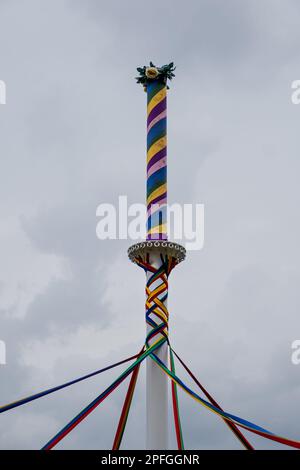 Un tiro a basso angolo di un classico inglese Maypole durante un festival di danza sotto un cielo nuvoloso Foto Stock