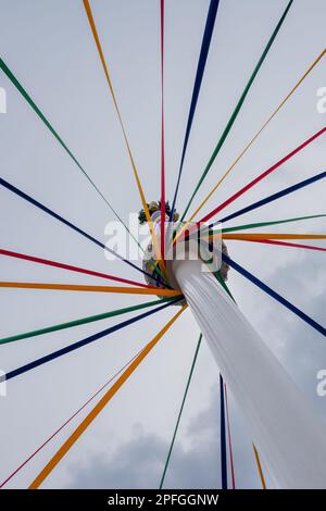 Un tiro a basso angolo di un classico inglese Maypole durante un festival di danza sotto un cielo nuvoloso Foto Stock