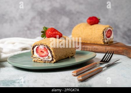 Torta di tronchi arrotolata. Torta alla fragola e alla crema su fondo di pietra. Dolci di pasticceria Foto Stock