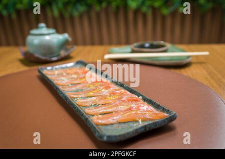 Deliziosi sashimi di salmone di prima qualità disposti su un elegante piatto fatto a mano. Foto Stock