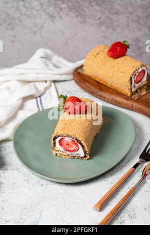 Torta di tronchi arrotolata. Torta alla fragola e alla crema su fondo di pietra. Dolci di pasticceria Foto Stock