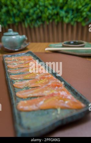 Deliziosi sashimi di salmone di prima qualità disposti su un elegante piatto fatto a mano. Foto Stock