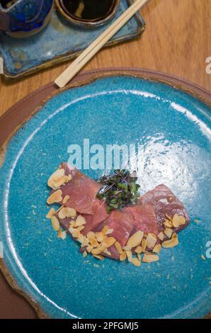 Deliziosi sashimi di tonno di prima qualità disposti su un elegante piatto fatto a mano. Foto Stock