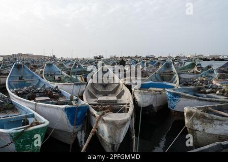 Un gruppo di vivaci barche da pesca blu e bianche a Nouadhibou, Mauritania, che catturano lo stile di vita e la tradizione marinara di questo villaggio costiero di pescatori Foto Stock