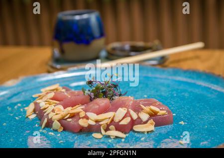 Deliziosi sashimi di tonno di prima qualità disposti su un elegante piatto fatto a mano. Foto Stock