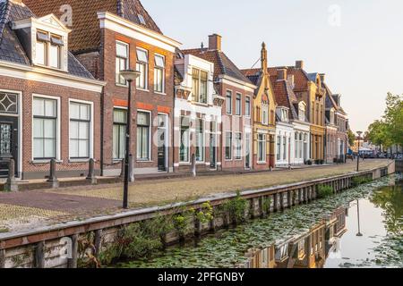 Vecchie case colorate e tradizionali lungo il canale nella pittoresca cittadina olandese di Bolsward in Frisia. Foto Stock