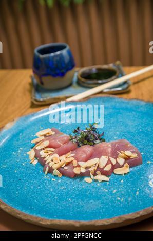 Deliziosi sashimi di tonno di prima qualità disposti su un elegante piatto fatto a mano. Foto Stock