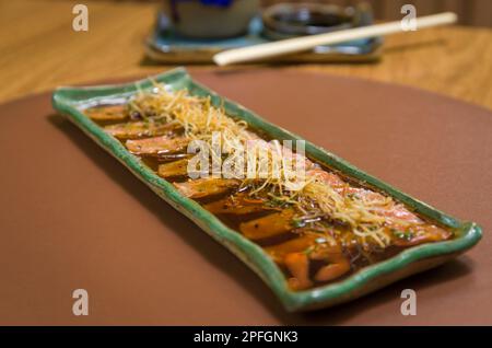 Deliziosi sashimi di salmone di prima qualità disposti su un elegante piatto fatto a mano. Foto Stock